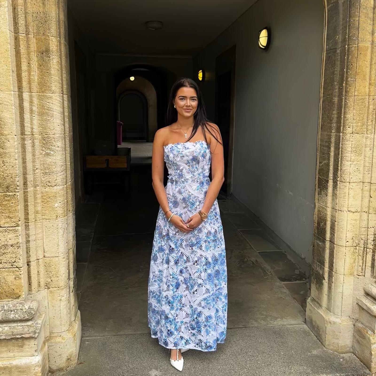 Annabelle Pamela in a blue lace dress beneath a stone archway