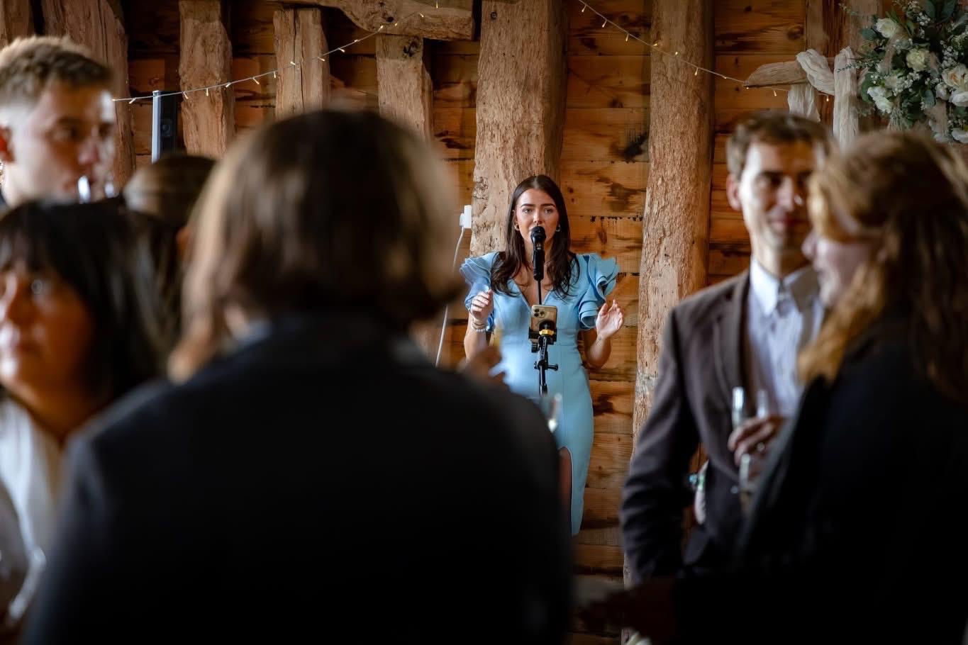 Annabelle singing to guests in a timber barn